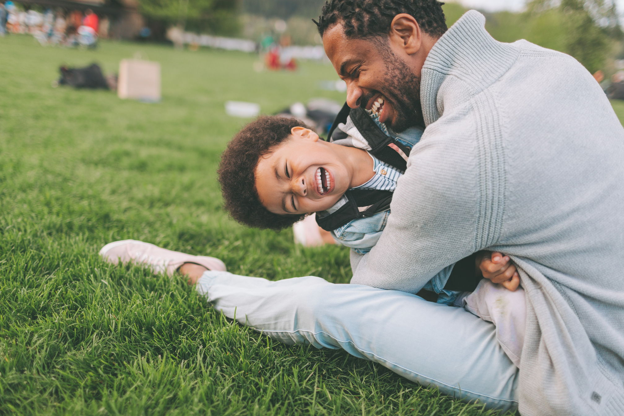 Happy Father Hugging His Laughing Son at the Park